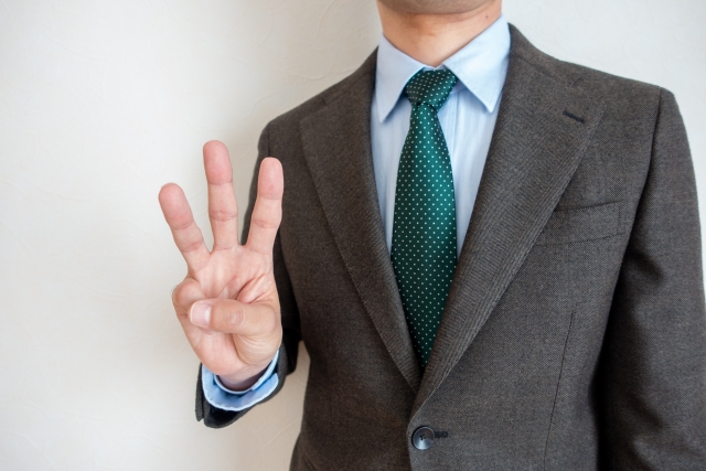 スーツ姿の男性が3本の指を示している