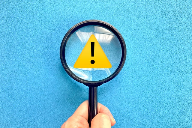 虫眼鏡で警告マークを確認する手元