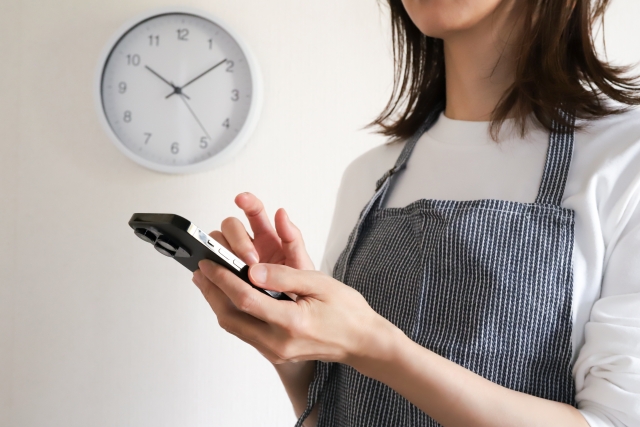 スマートフォンを操作するエプロン姿の女性